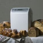 White breadmaker on table with different types of loaves around