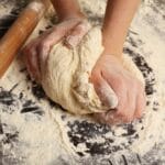 Hands kneading dough on flour dusted board
