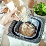 Woman pouring ingredient into bread maker