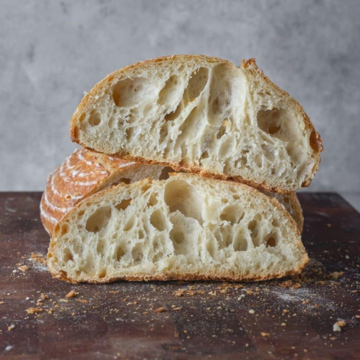 Partialy sliced loaf of bread on wooden pad