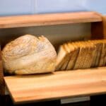 Loaf of bread, slices of bread in wooden bread box
