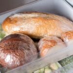Loaves of bread in palstic bags in freezer shelf with vegetable