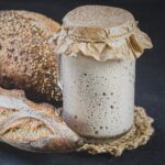 Sourdough in glass jar next to loafs of bread