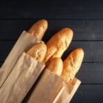 Baguettes in paper bags on black table