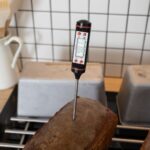 Kitchen thermometer in baked loaf of bread
