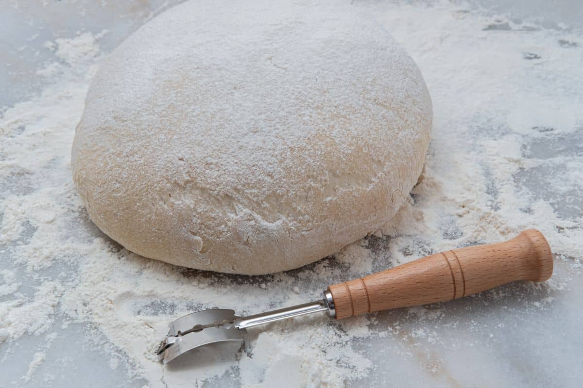 Bread lame with bread dough on spilled flour