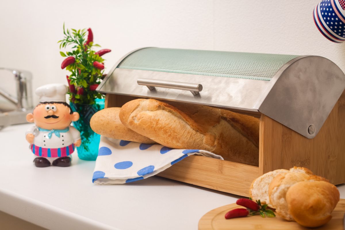 Baguettes and cloth wipe in bread box on table with wooden pad with bread and peppers, toy and peppers in cup