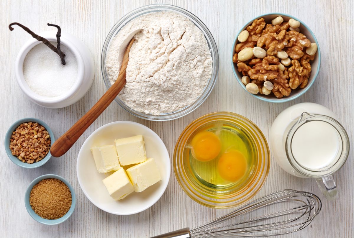 Baking ingredients in small bowls on white table, top view