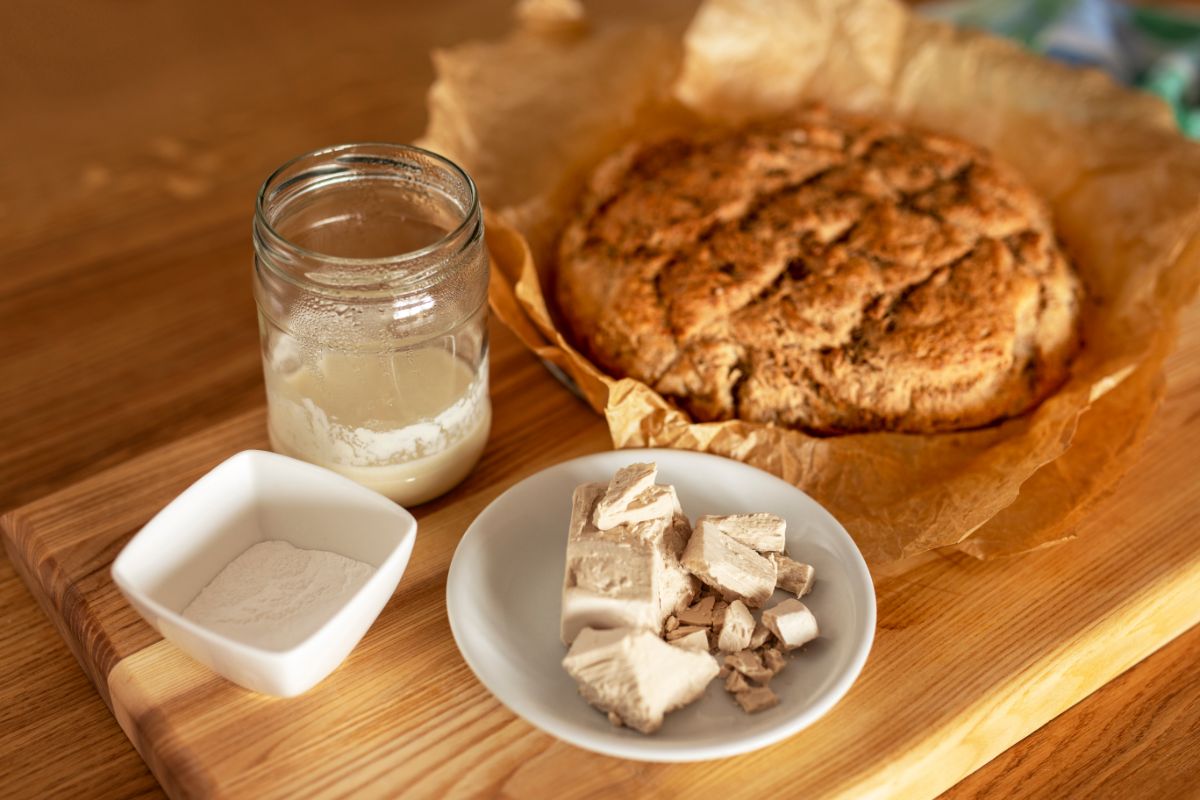 Varieteis of yeast on wooden cutting board with freshly baked loaf of bread on paper sheet