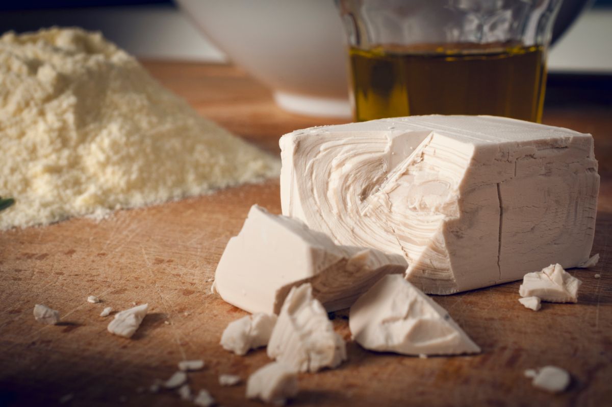 Block yeast on table with flour and glass cup