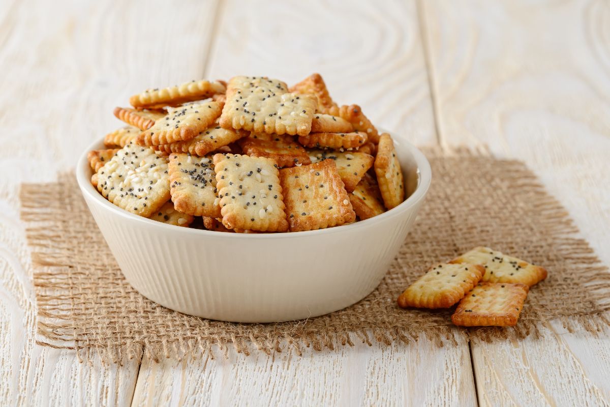 White bowl full of crackers on cloth pad on wooden table