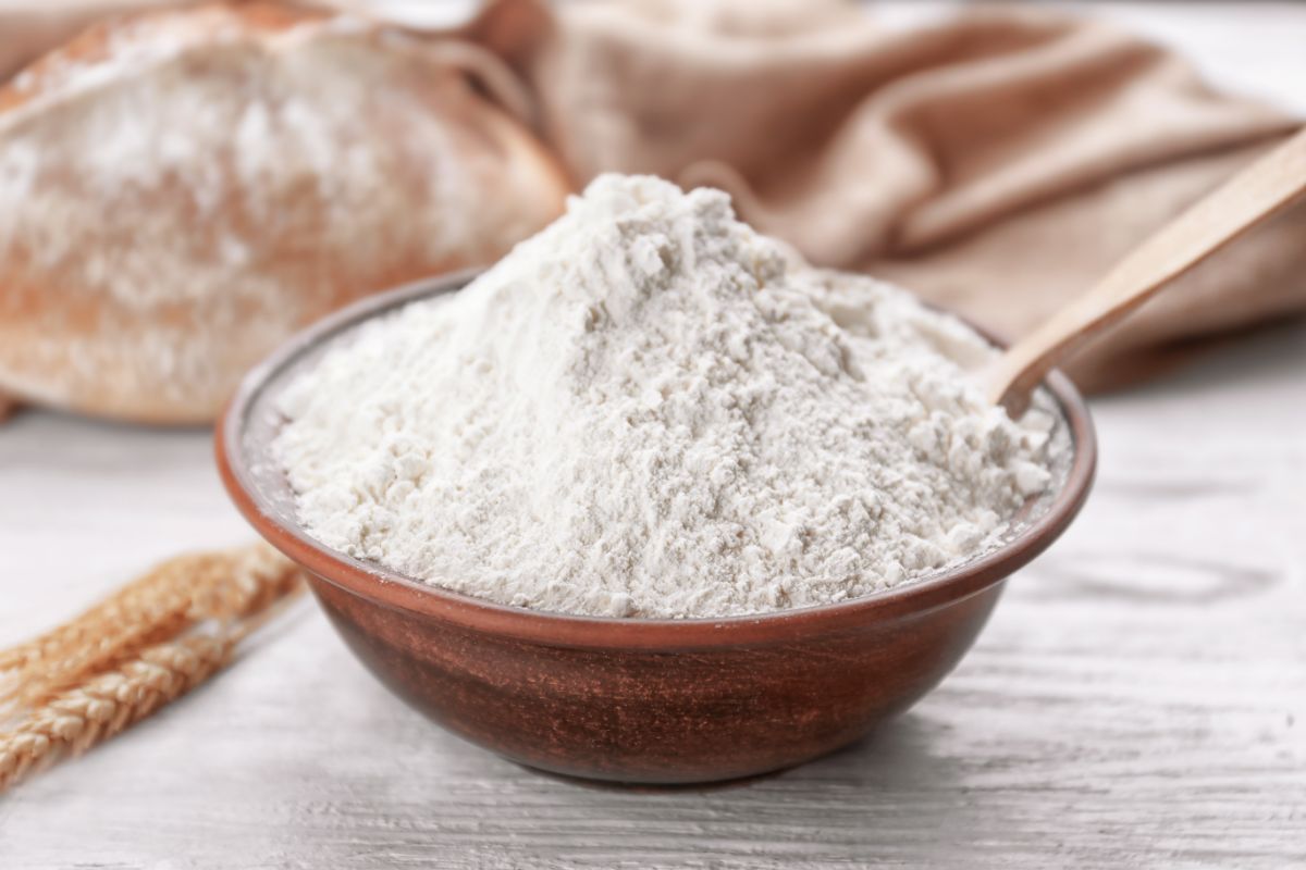 Bowl of flour with wooden spoon, Loaf of bread and cloth in the background