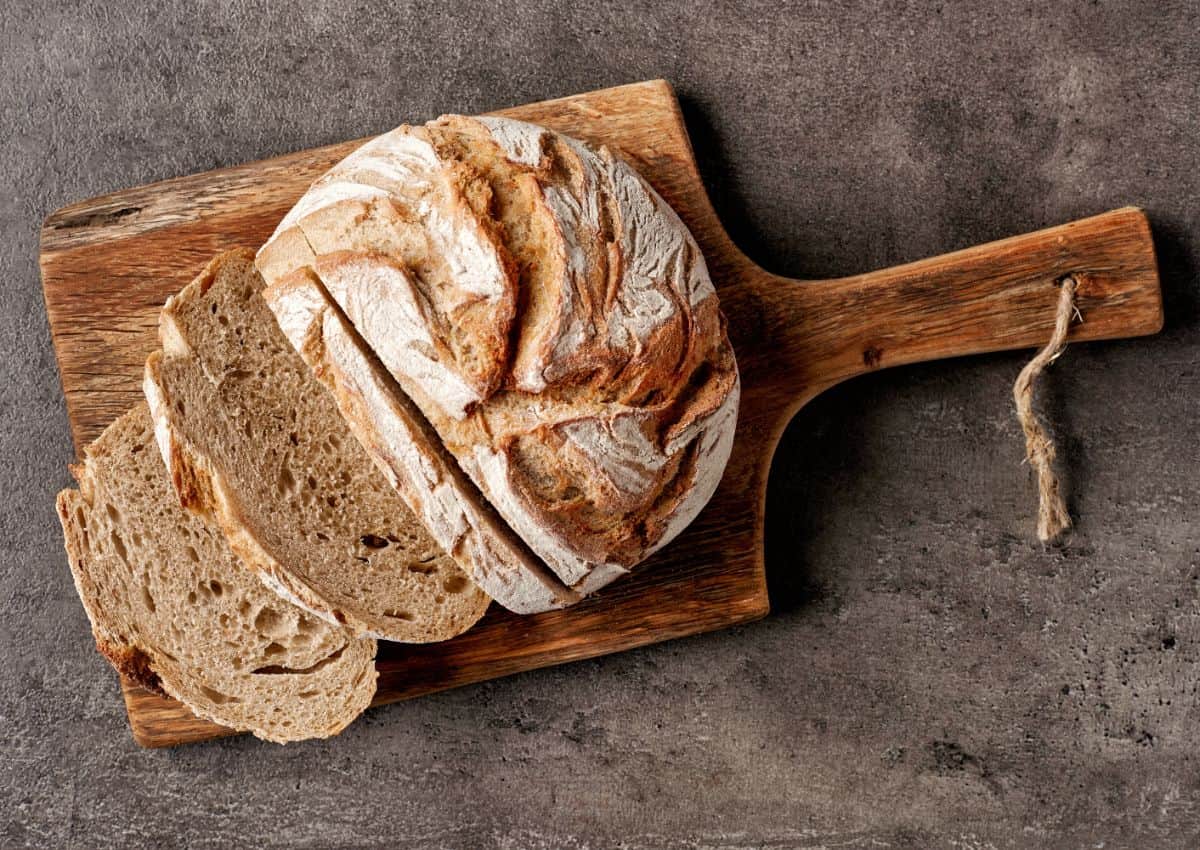 Loaf of bread partialy sliced on wooden pad