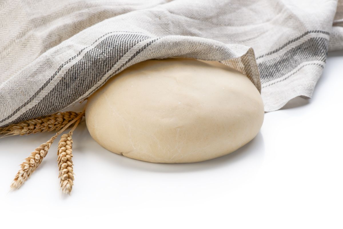 Bread dough partially covered by cloth wipe on white background