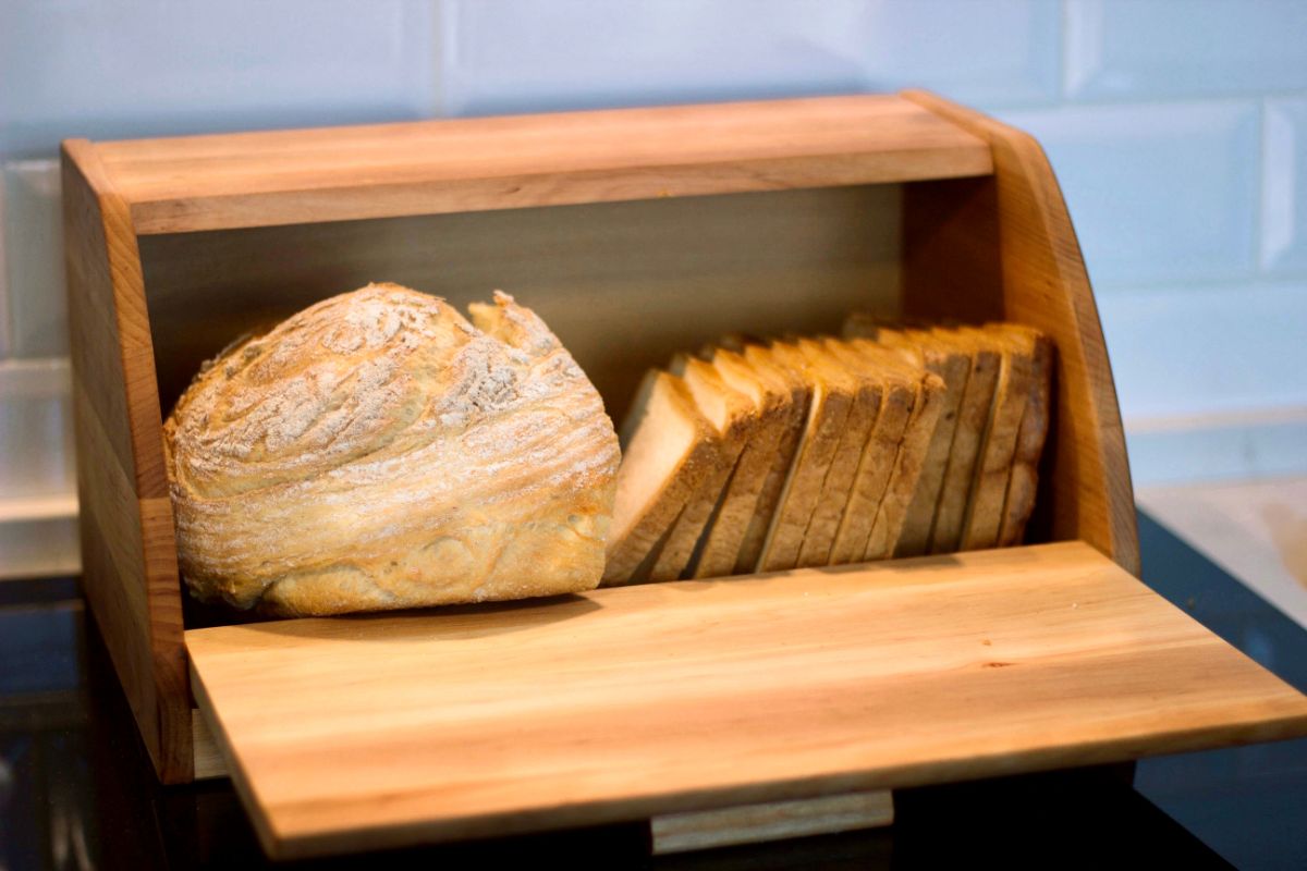 Loaf of bread and slices of bread in wooden bread box