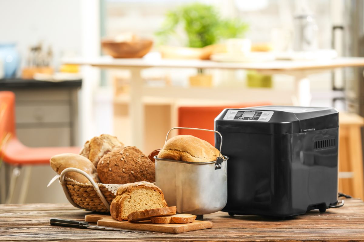 Black bread maker with loaves of bread on table in kitchen