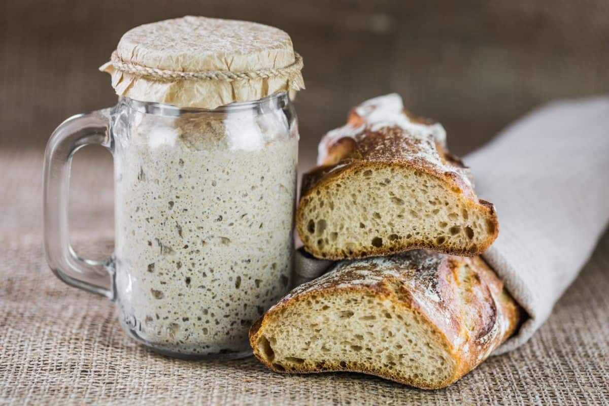 Bread yeast in glass jar next to sliced loaf of bread