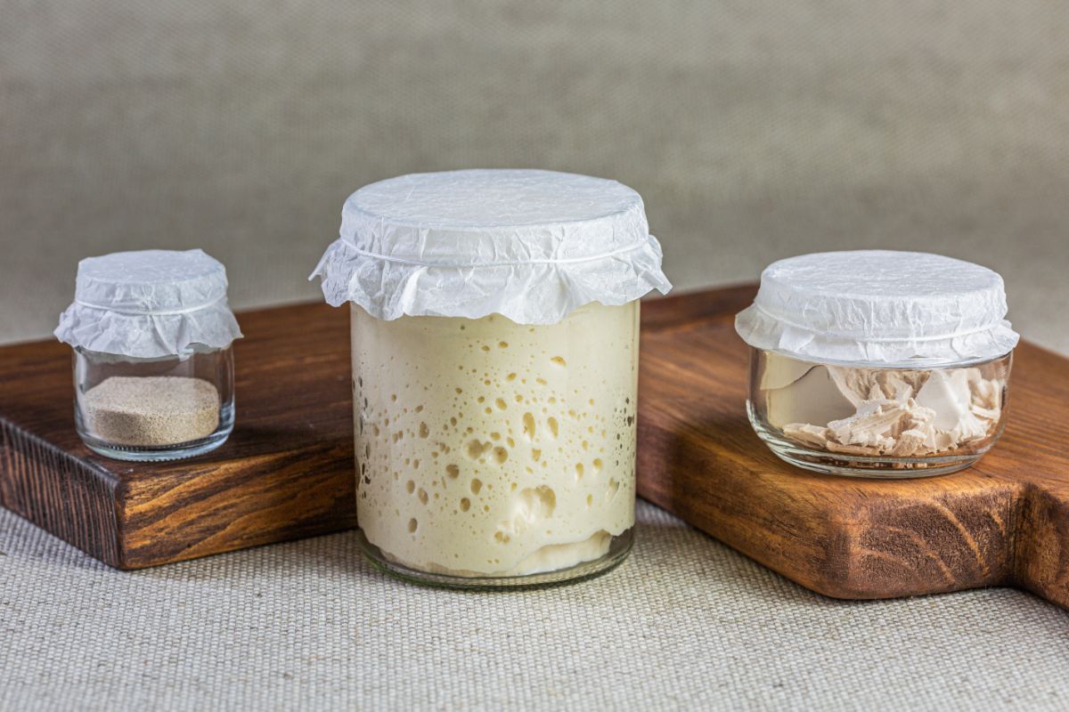 Different types of yeast in glass jars on wooden boards and table