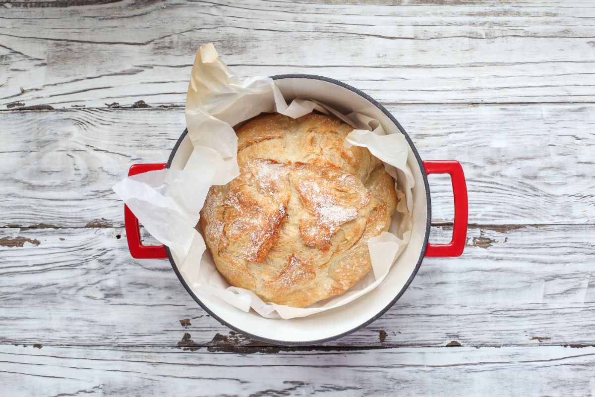 Loaf of bread in red ducht oven with paper sheet