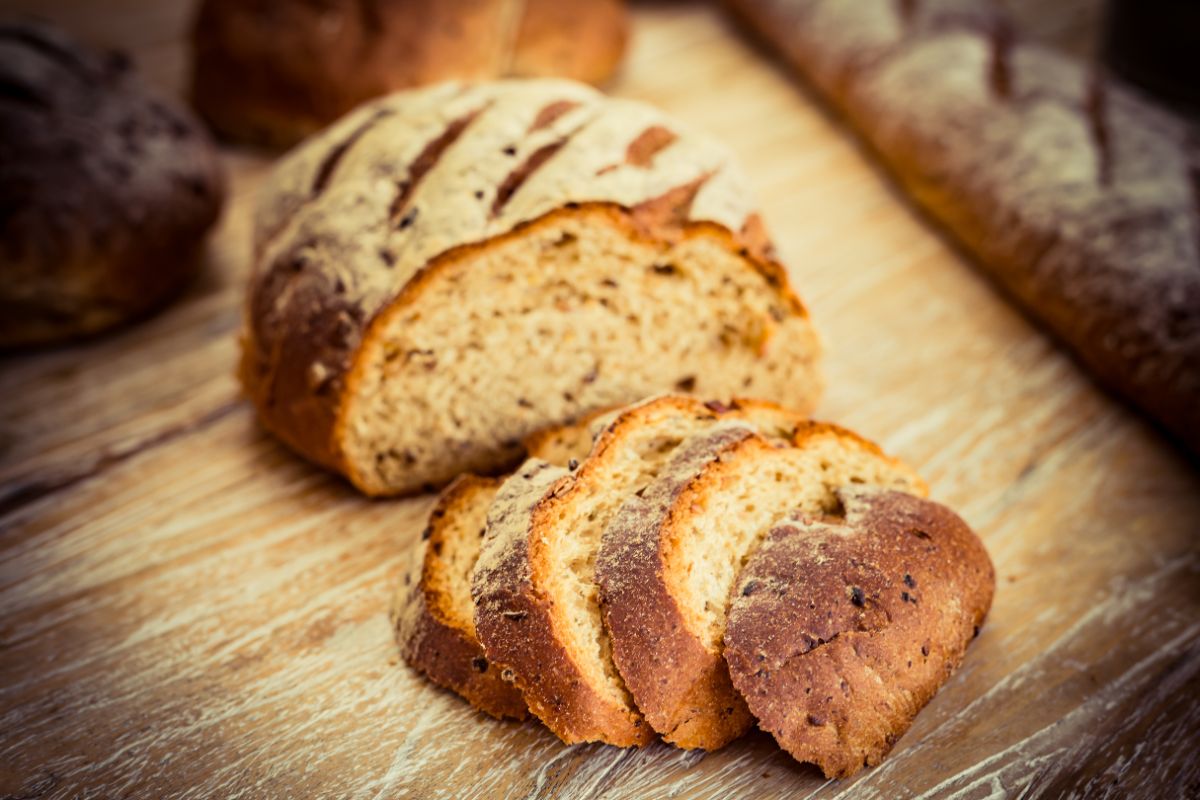 Loaf of ezekiel bread partialy sliced on wooden pad