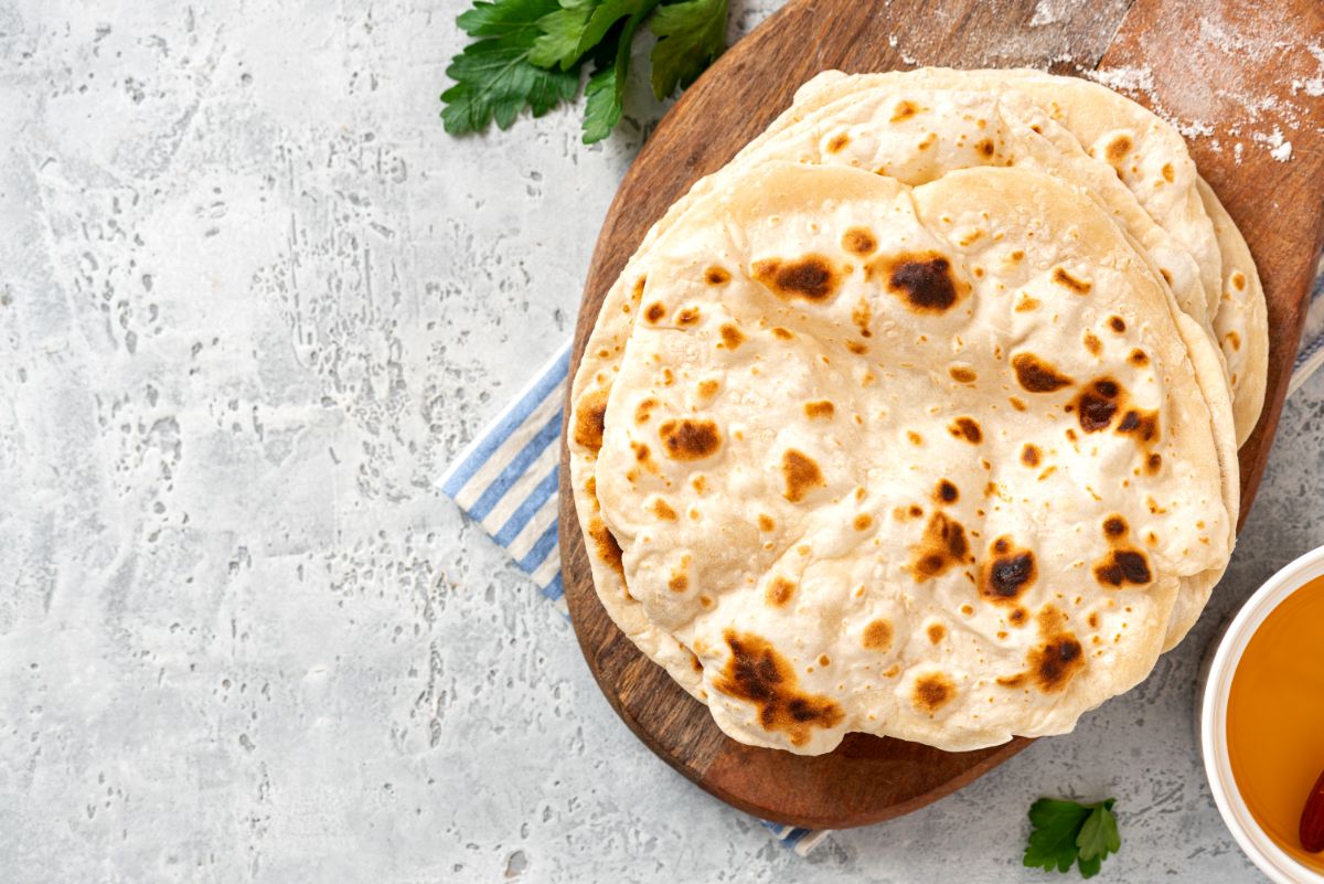 Flatbread on wooden pad, top view