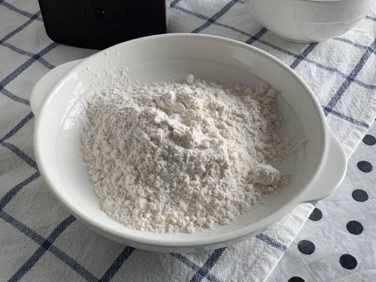 White flour in white bowl on blue white table cloth