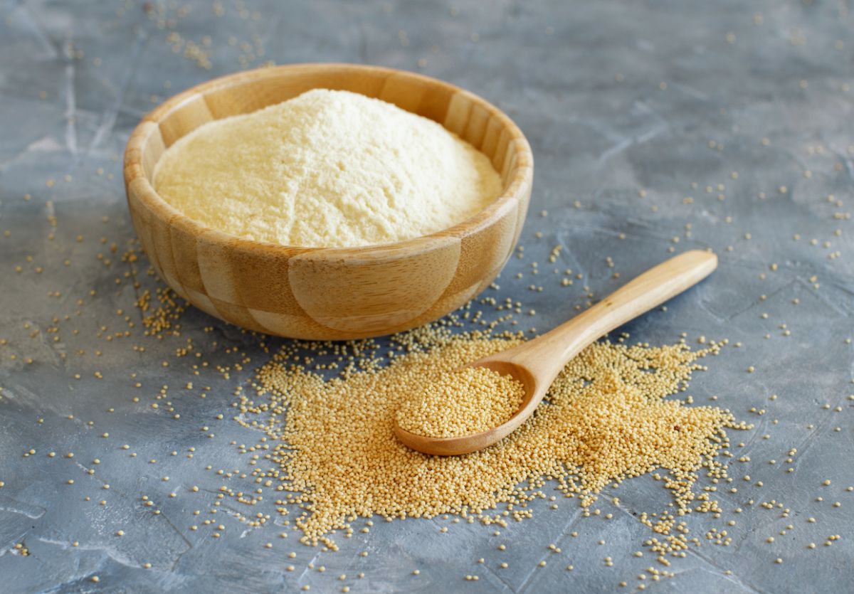 Flour in wooden bowl on table with spoon and scattered ingredient around