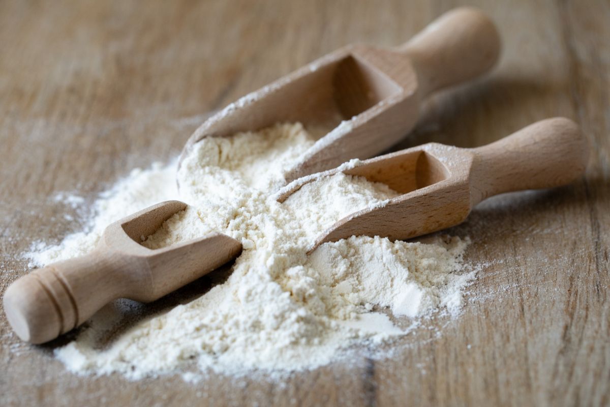 Three wooden spoon with white flour on table