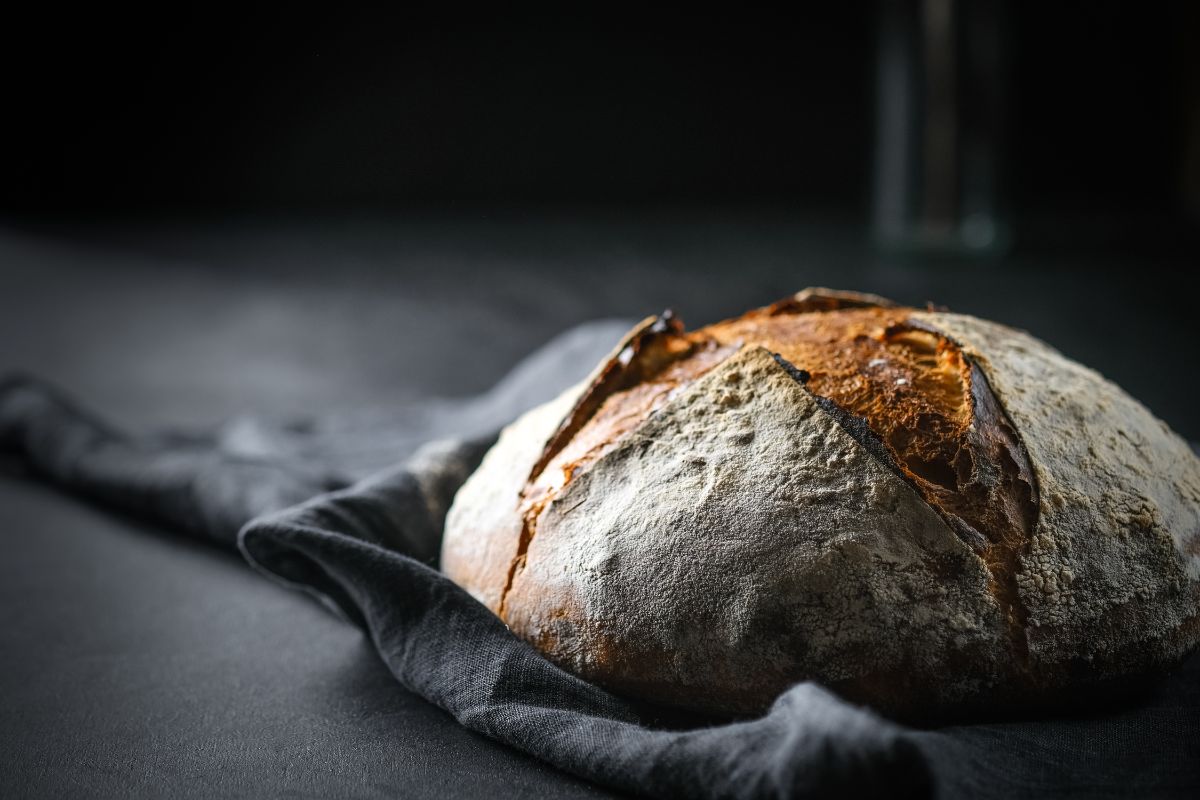 Freshly baked sourdough loaf of bread on black cloth