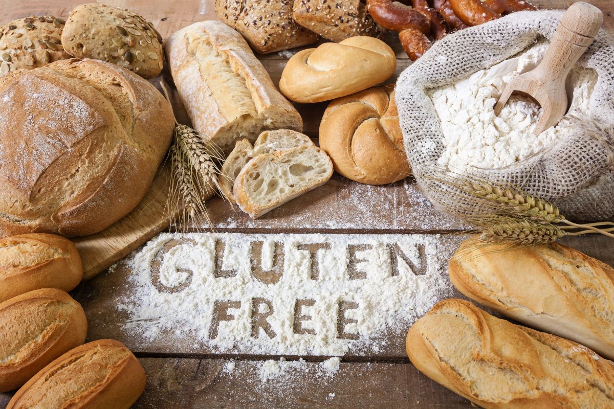Gluten free sign in spilled flour with loaves of bread and ingredients around