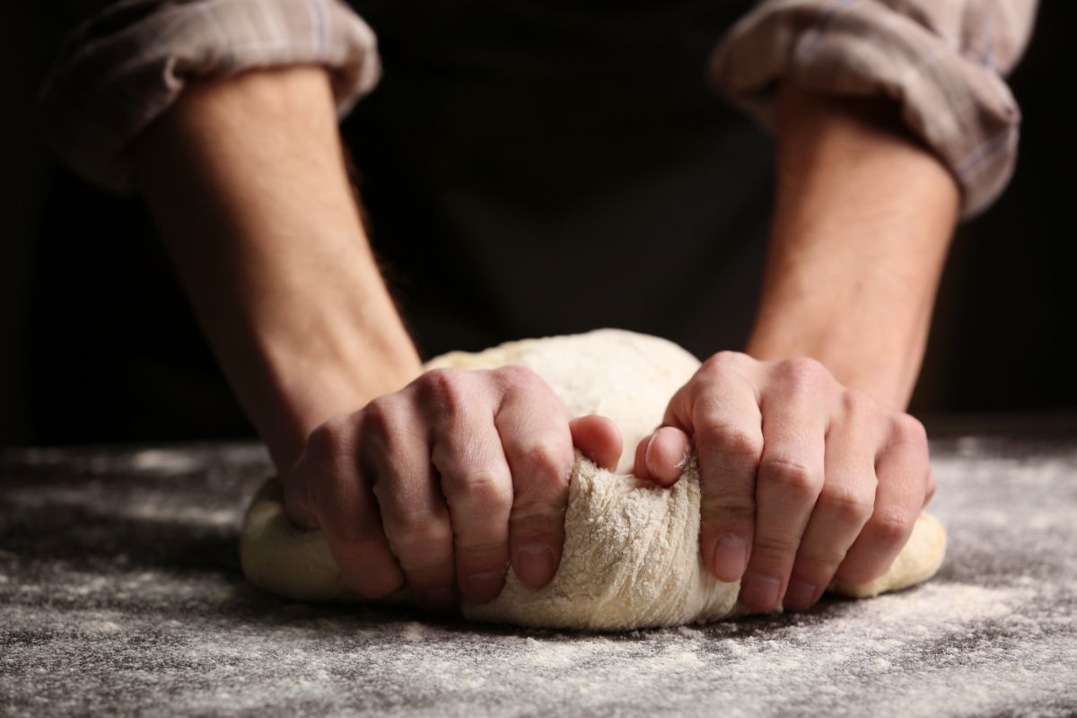 Hands kneading dough on flour dusted board