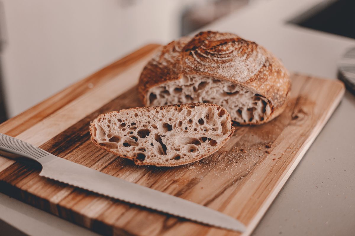 Homemade loaf of bread on wooden cutting board with knife