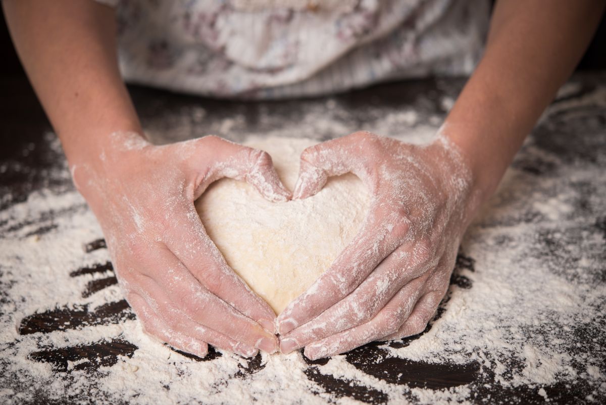 Knead dough by hands on board with spilled flour