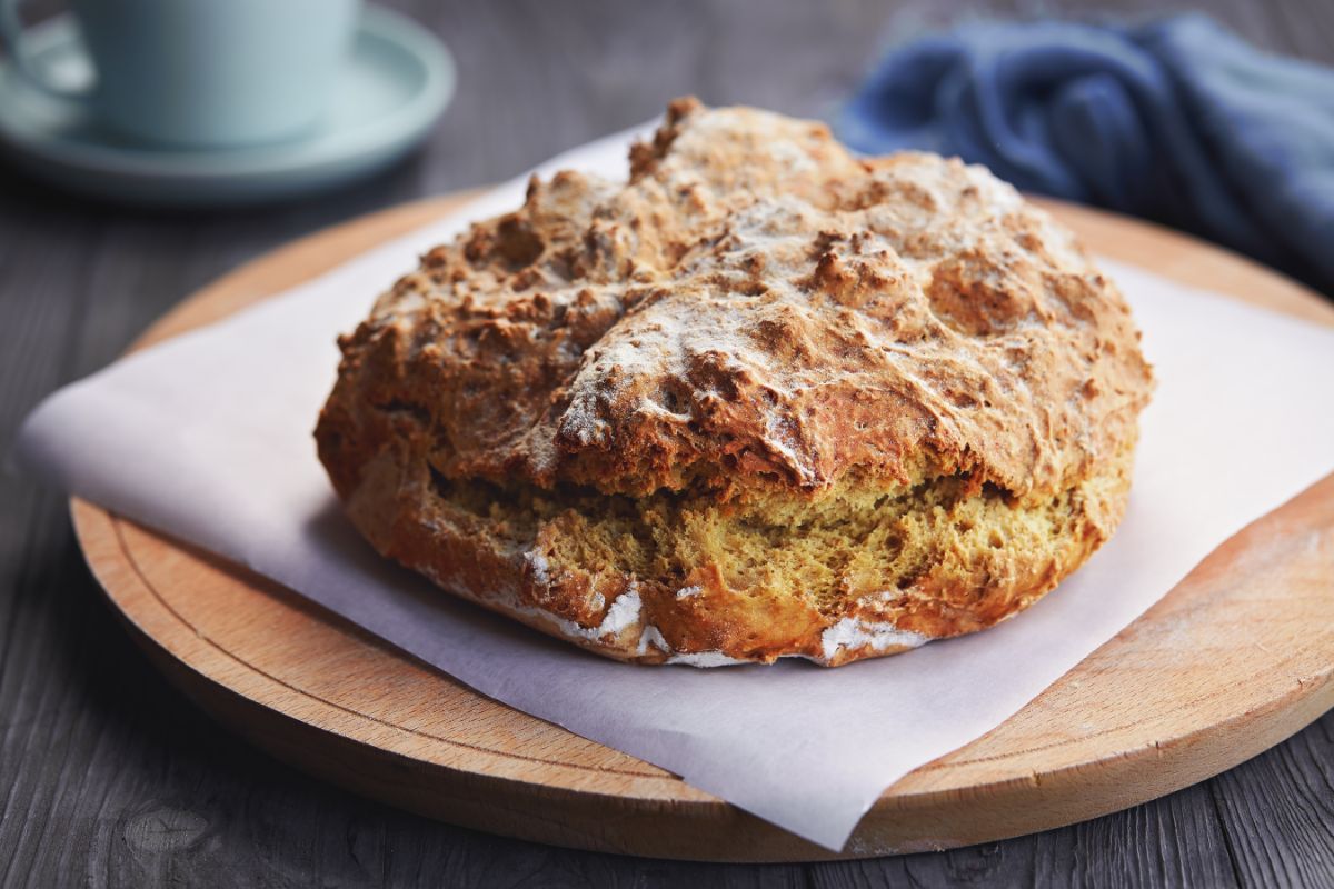 Loaf of bread on wooden pad with pachment paper sheet