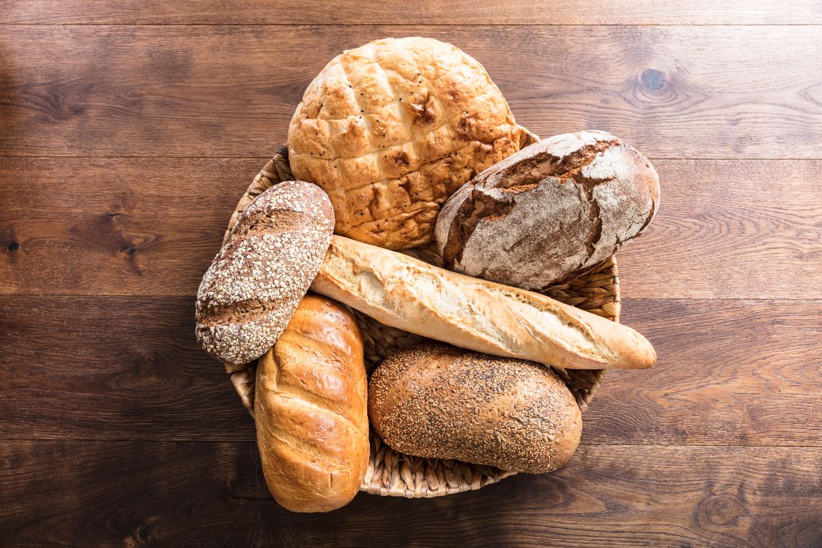 Different loaves of bread in wooden basket on wooden table