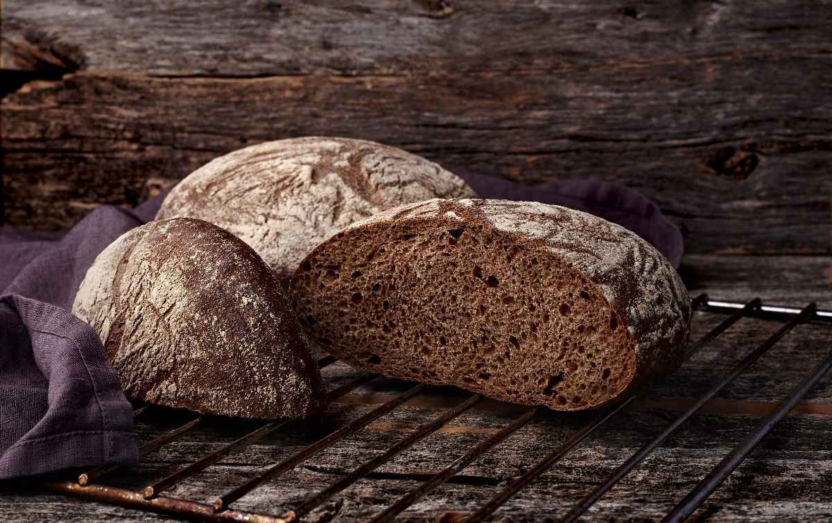 Loaves of bread on cooling grid next to cloth wipe