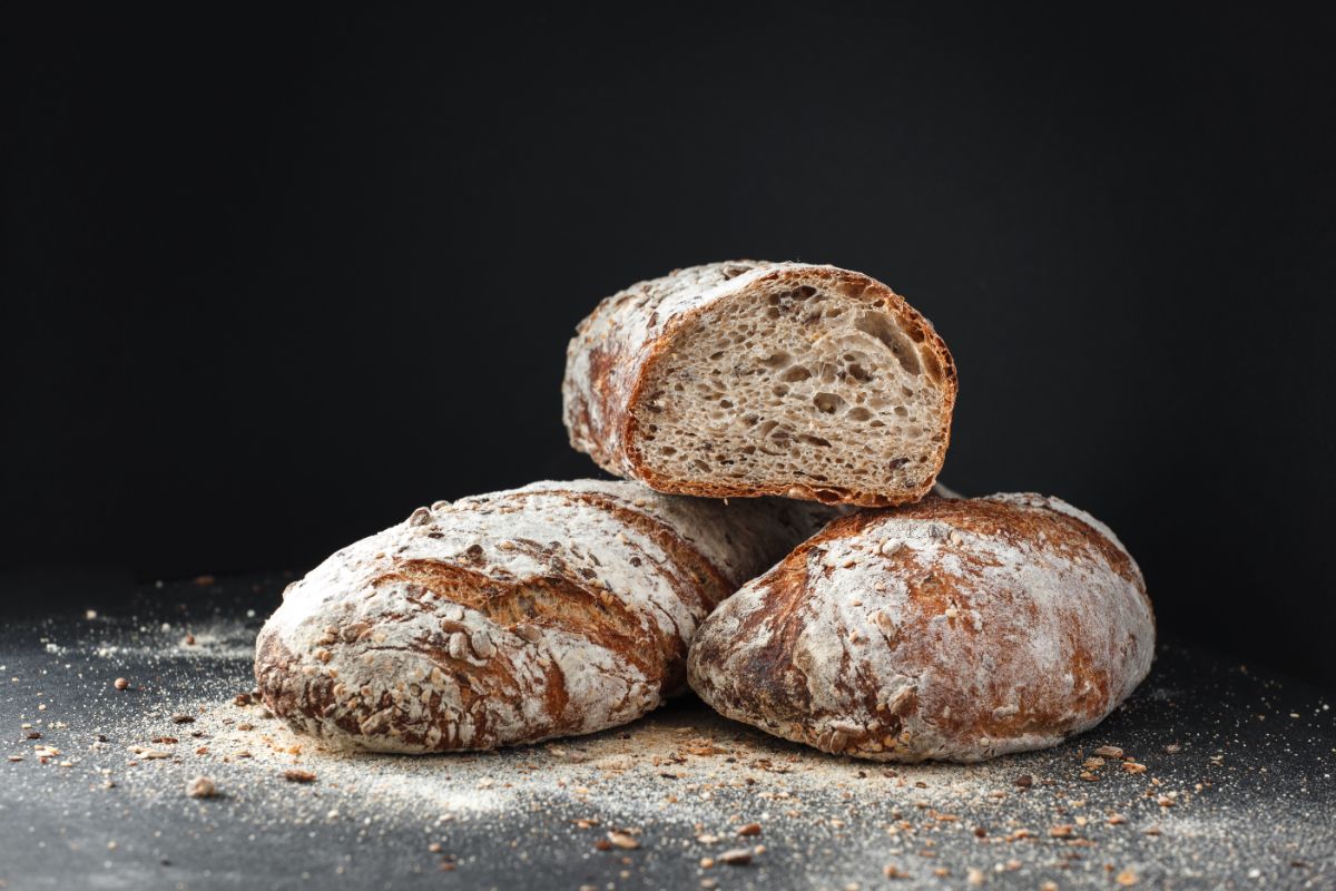 Fresh loaves of bread on black table with crumbs