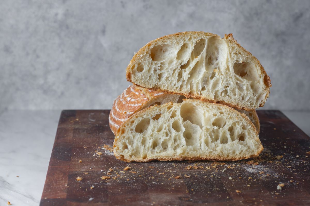 Partialy sliced loaf of bread on wooden pad