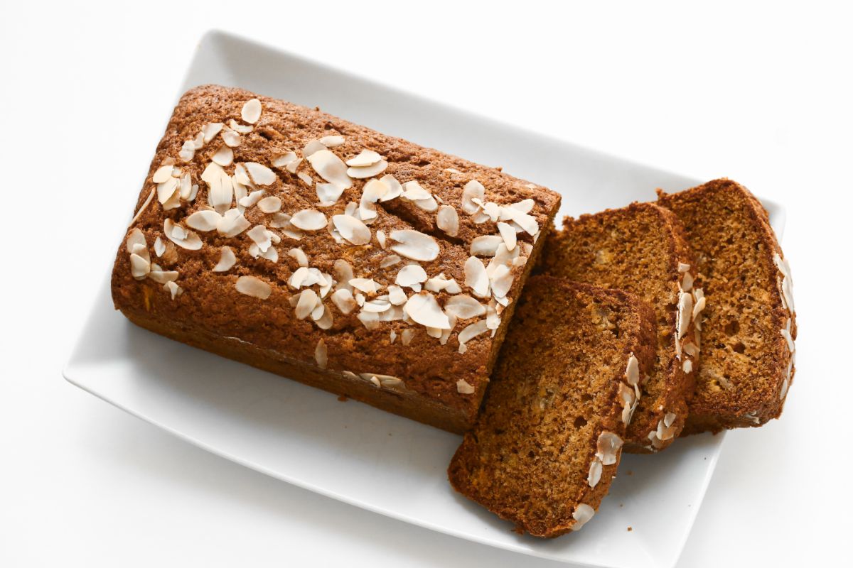 Loaf of quick bread partialy sliced on white plate