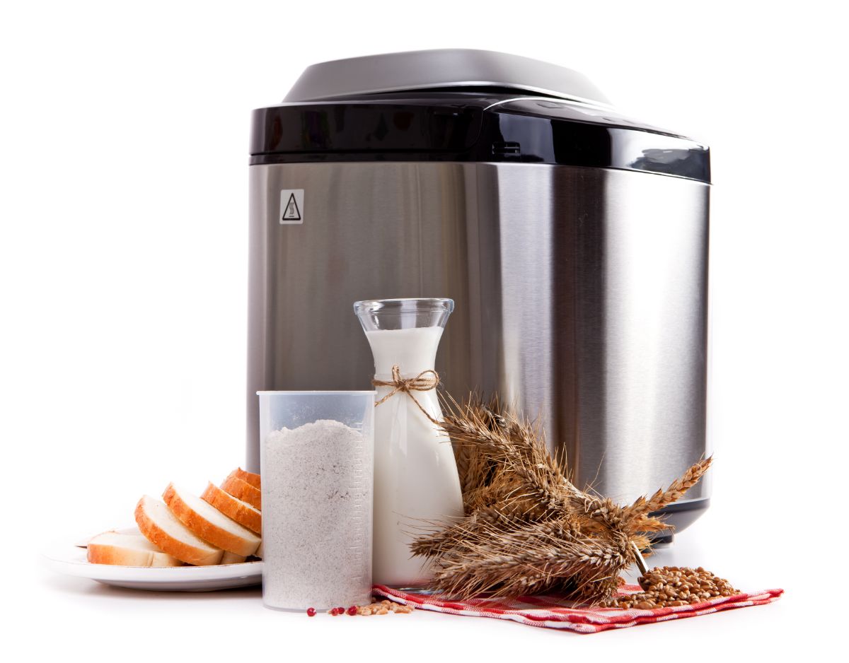Silver bread maker with ingredients on white background