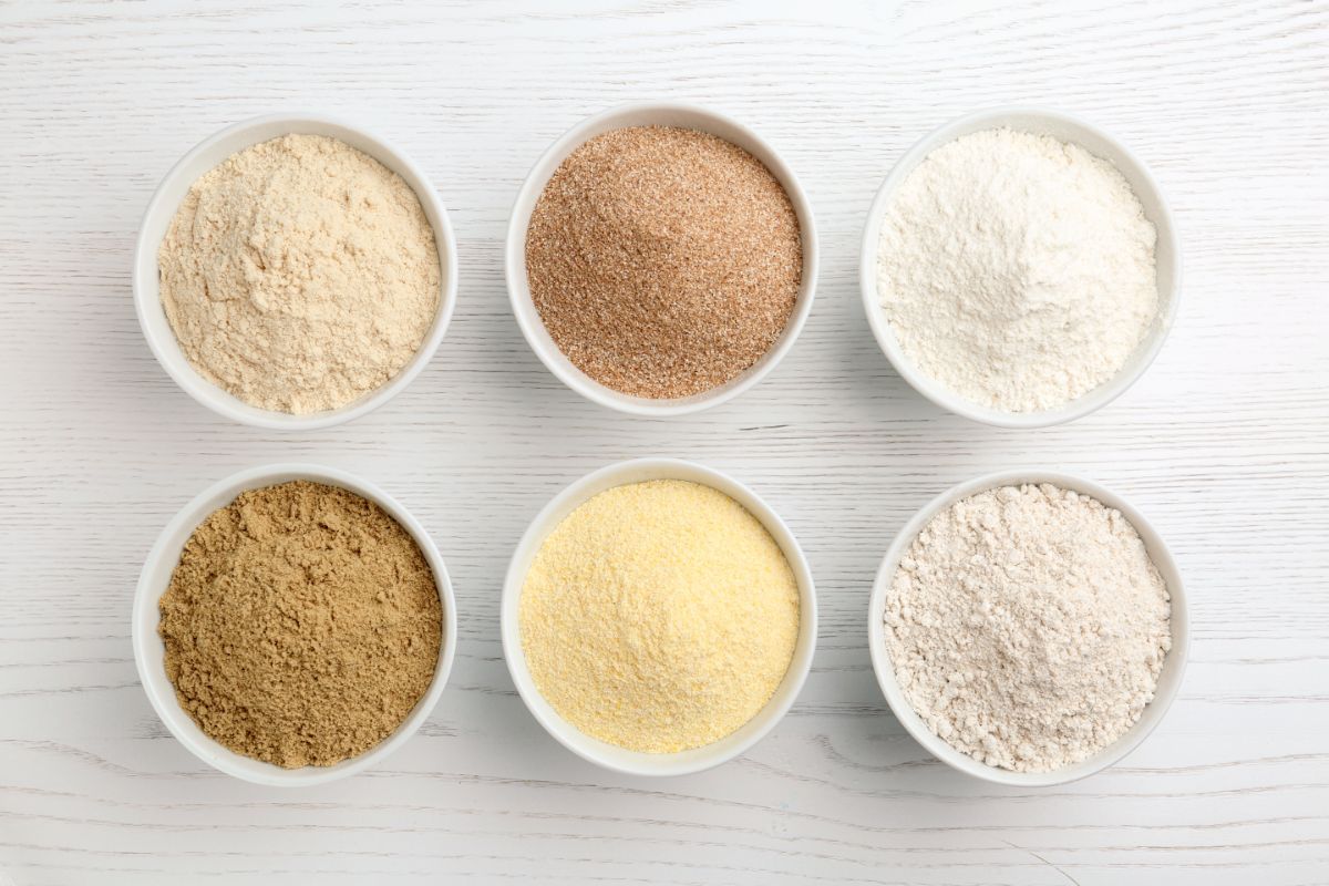 Six bowls of different types of flour on gray table
