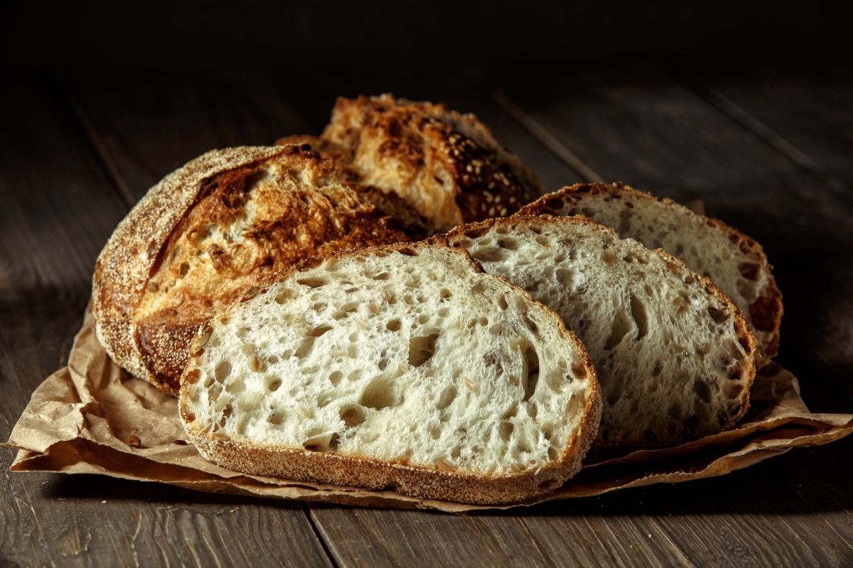 Slices of fresh sourdough bread on paper sheet on wooden table