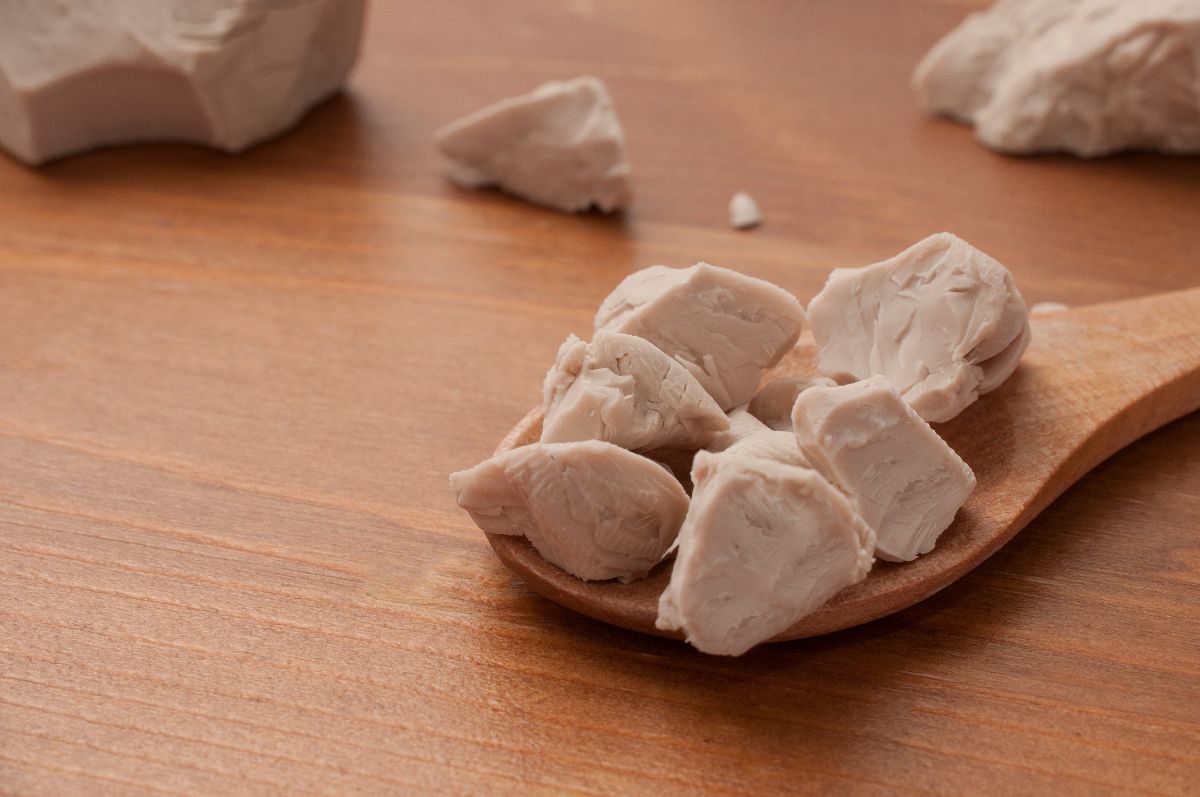 Crumbled block yeast on wooden spoon and table