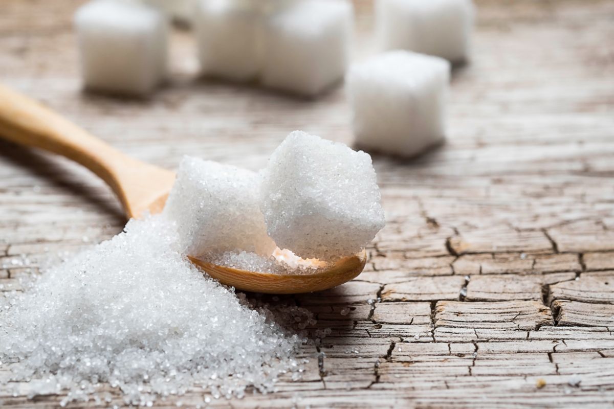 Sugar on wooden spoon and on table