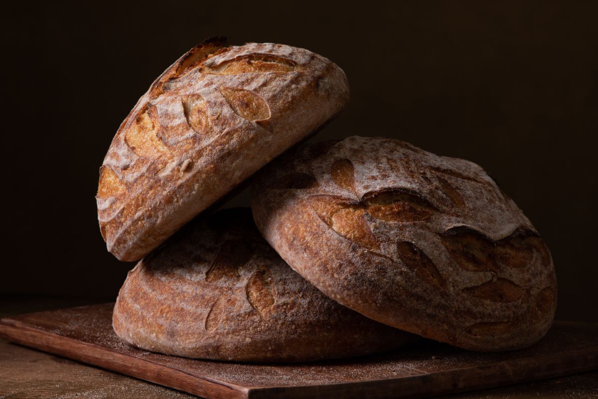 Freshly baked loeaves of sourdough bread on wooden pad