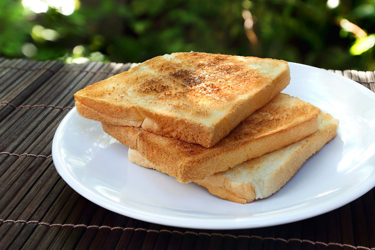Toast bread slices on white plate on black table