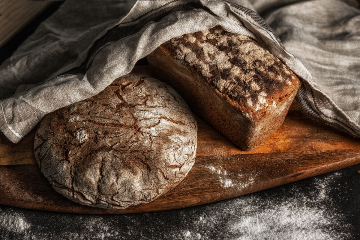 Traditional loaves of bread on wooden board partially covered with cloth